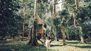 dos personas sentadas en el césped frente a un árbol en The Vatika Resort and Spa en Ao Nang