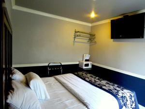 a bedroom with a bed and a flat screen tv at La Bonita Inn Motel in Long Beach