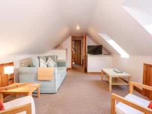 a living room with a couch and a tv at Wisteria Cottage in Gayton