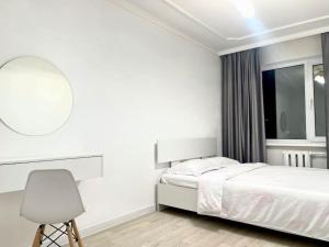 ein weißes Schlafzimmer mit einem Bett und einem Stuhl in der Unterkunft Квартира в самом центре in Qaraghandy