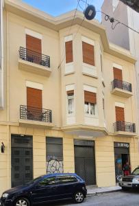 un coche negro estacionado frente a un edificio amarillo en De lenco Residence 4, en Atenas