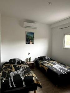 1 dormitorio con 2 camas y 1 manta de jirafa en L'escale du sud sauvage en Petite Île