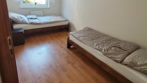 two beds in a room with a wooden floor at Trzy Szczęścia in Zielona Góra