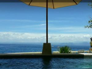 a view of the ocean from a pool with an umbrella at Nusa Lembongan Villa Shambala in Nusa Lembongan +13 photos