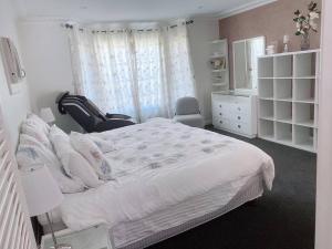1 dormitorio con 1 cama y 1 silla en 4 BR House - Walk to Station & Nepean Hospital, en Kingswood