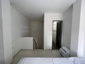 ein weißes Zimmer mit einem Bett und einer Treppe in der Unterkunft apartaestudió dúplex Neiva in Neiva