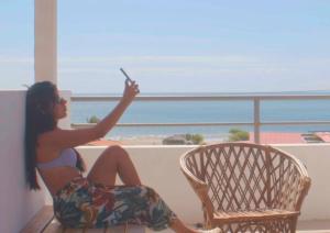 a woman sitting in a chair taking a picture of the beach at Casa Norte North Beach in Los Órganos