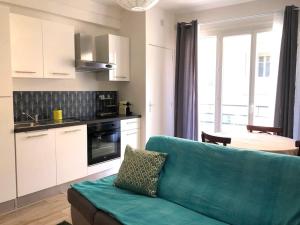 a living room with a blue couch and a kitchen at Cannes centre-deux pièces-tout confort in Cannes