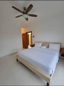 a bedroom with a large white bed with a ceiling fan at Luxury Condo. Steps From The Beach! in San Felipe de Puerto Plata