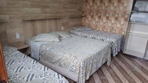 3 camas en una habitación con suelo de madera en Hotel Majestic, en Pelotas