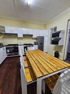 uma cozinha com uma mesa de madeira e armários brancos em 11 on Elizabeth em Mount Road