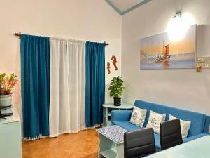 een woonkamer met een blauwe bank en blauwe gordijnen bij Villa By The Beach Goa in Benaulim