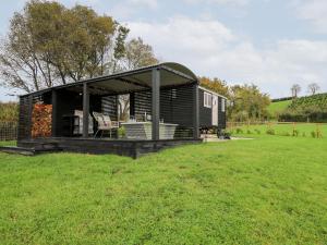 uma pequena casa preta sentada num campo em Dragonfly Shepherd's Hut em Aberaeron