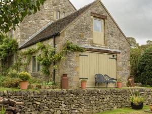 a stone house with a garage with two chairs at Pail End in Brassington