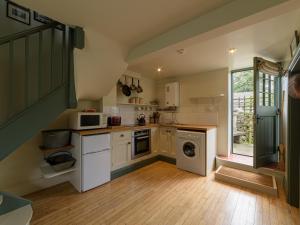 a small kitchen with white appliances and a window at Pail End in Brassington