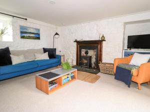 a living room with a blue couch and a fireplace at Beech Cottage in Lochs