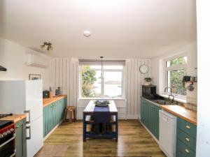 cocina con armarios verdes y nevera blanca en Beech Cottage, en Lochs