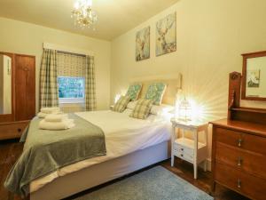 a bedroom with a bed and a dresser and a window at Knoll Cottage in Bakewell