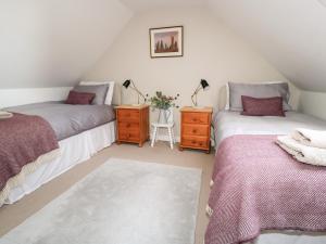 Schlafzimmer im Dachgeschoss mit 2 Betten und einem Tisch mit Lampen in der Unterkunft Beech Cottage in Lochs