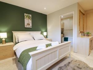 a bedroom with a large bed with a green wall at 2 Dove Cottage in Uttoxeter