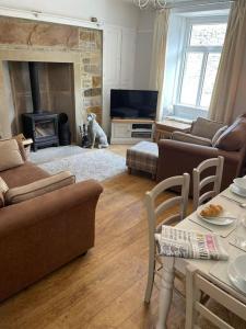 a living room with a dog sitting in front of a fireplace at Hawksworth Cottage - Grassington Village Location in Grassington