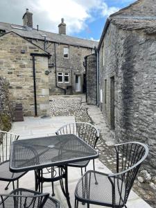 a patio with a table and chairs in front of a building at Hawksworth Cottage - Grassington Village Location in Grassington