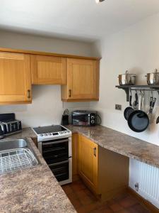 a kitchen with wooden cabinets and a stove top oven at Hawksworth Cottage - Grassington Village Location in Grassington