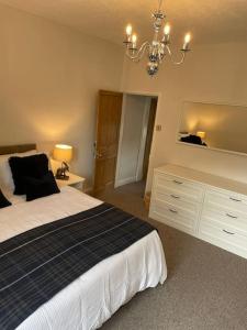 a bedroom with a large bed and a chandelier at Hawksworth Cottage - Grassington Village Location in Grassington