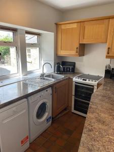 a kitchen with a washing machine and a sink at Hawksworth Cottage - Grassington Village Location in Grassington