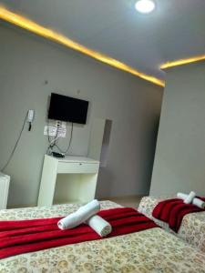 2 Betten in einem Zimmer mit einem TV an der Wand in der Unterkunft Marcone Lima - Chalés in Barreirinhas