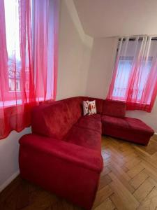a red couch in a living room with red curtains at Appartamento di Vacanze in Muralto