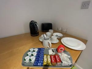 a table with plates and cups and a tray of food at Modern Guest house with private entrance in Manchester