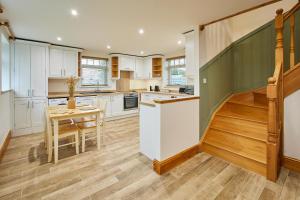 a kitchen with white cabinets and a table and a staircase at Host & Stay - Fawcett Cottage in Tollerton +12 photos