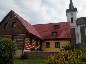 une église avec un toit rouge et une tour d'horloge dans l'établissement Chata Dáša, à Kořenov