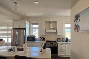 cocina con armarios blancos y nevera de acero inoxidable en Lakehouse with Rooftop View, en Bowmanville