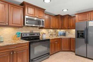 a kitchen with wooden cabinets and stainless steel appliances at The Salty Cove IRB in Clearwater Beach