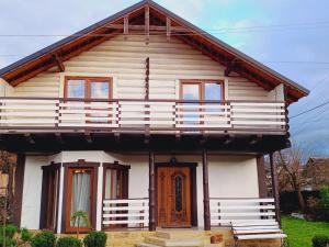 Casa blanca con puerta de madera y balcón en Villa Zgarda1, en Mykulychyn