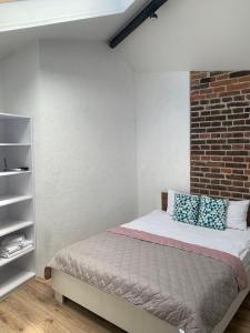 ein Schlafzimmer mit einem Bett und einer Ziegelwand in der Unterkunft Center Lviv Avenue 23 in Lwiw