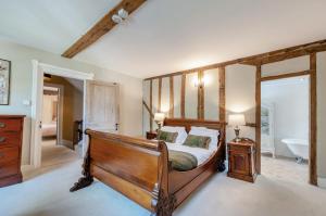 - une chambre avec un lit en bois et une salle de bains dans l'établissement Perry Farm by Bloom Stays, à Canterbury