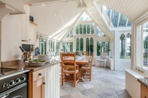 a kitchen with a table in a conservatory with windows at Perry Farm by Bloom Stays in Canterbury
