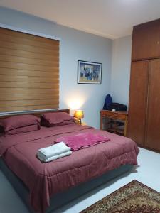 een slaapkamer met een groot bed met een houten hoofdeinde bij Sri Lagenda Apartment Langkawi in Kuah