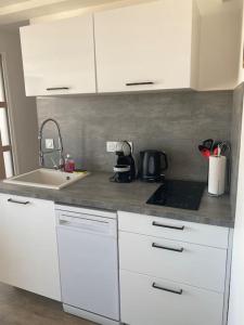 una cocina con armarios blancos y fregadero en Appartement en plein cœur du centre ville, en Les Sables-dʼOlonne