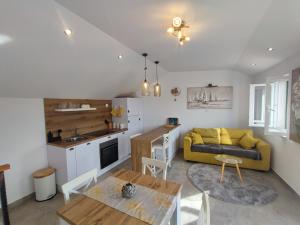 a living room with a yellow couch and a kitchen at Bobelino in Povlja