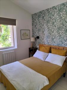 a bedroom with a bed and a wall with floral wallpaper at Gîte Les Rapières in Gordes