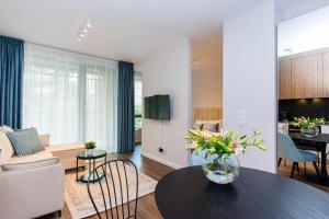 a living room with a vase of flowers on a table at Scala Rentyear Apartments in Gdańsk