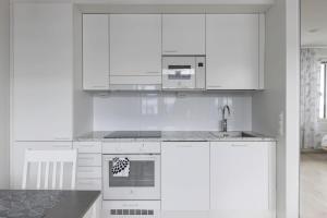 a white kitchen with white cabinets and a sink at Beautiful Modern City Apartment in Kuopio