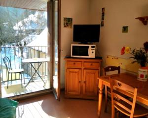 uma sala de estar com uma mesa e uma televisão e uma varanda em Studio Gavarnie em Gavarnie