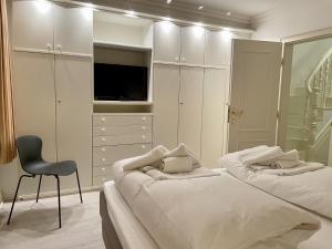 a white bedroom with two beds and a chair at Sunny-Beach in Kampen