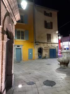 an empty street with a yellow building with blue doors at #2 Studio # Place charmante in Toulon