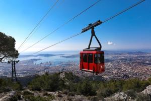 a red cable car flying over a city at #2 Studio # Place charmante in Toulon